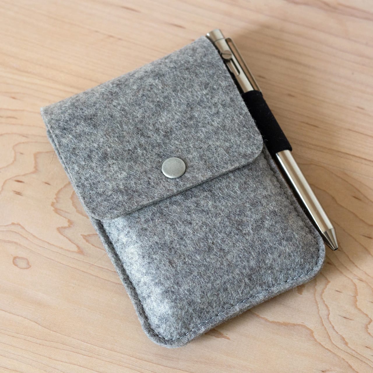 Textured gray felt pouch for paper cards with snap button flap and elastic pen holder loop.